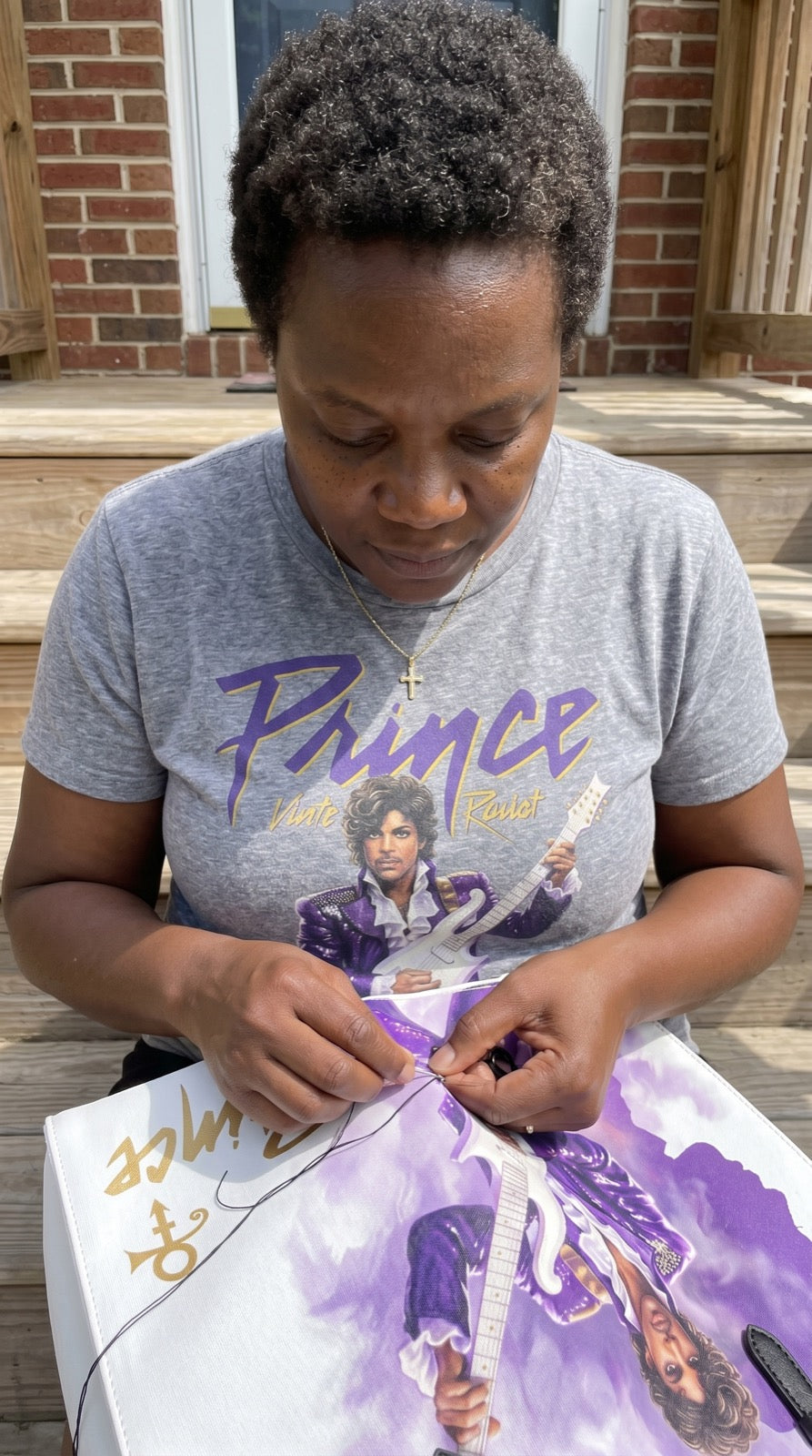 Hands hand-stitching a Prince tribute tote bag