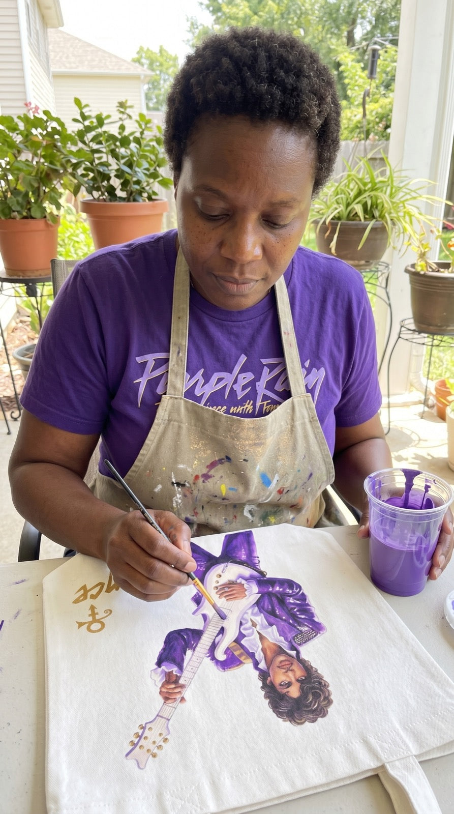 Hands painting a Prince tribute tote bag